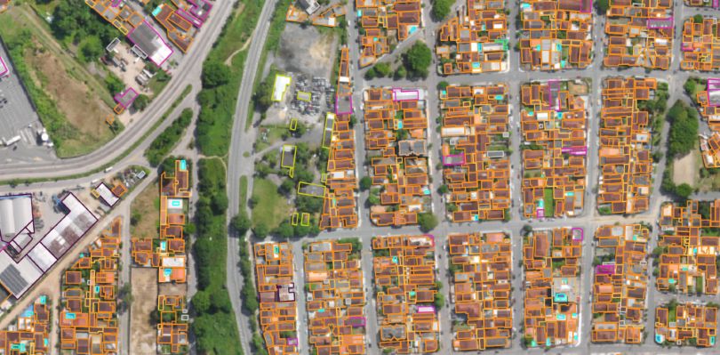 Imagem aérea da plataforma Geopixel voltada à Reforma Tributária municípios, exibindo quadras residenciais densamente ocupadas com lotes e edificações delimitados por contornos coloridos (laranja, amarelo, magenta e ciano) para identificação cadastral.